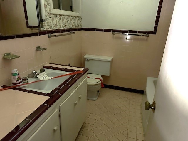 bathroom with tile patterned flooring, vanity, tile walls, and toilet