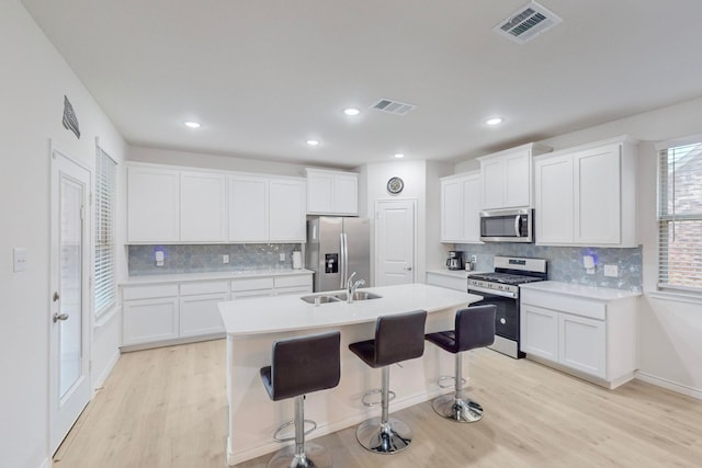 kitchen featuring a kitchen island with sink, sink, stainless steel appliances, and white cabinets