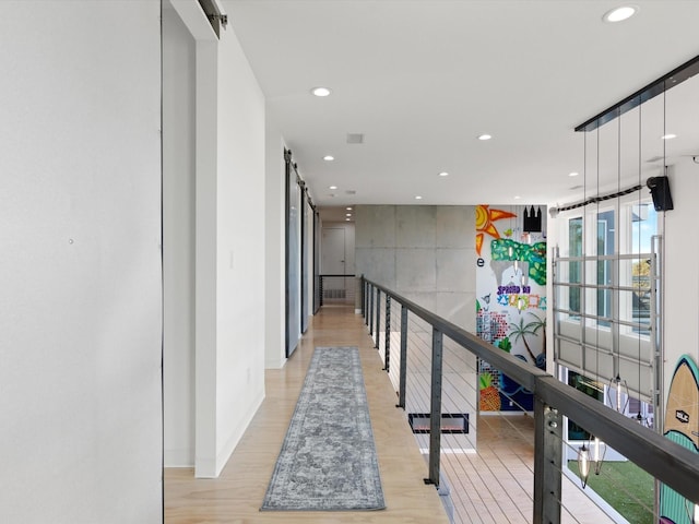 corridor with light hardwood / wood-style floors and a barn door