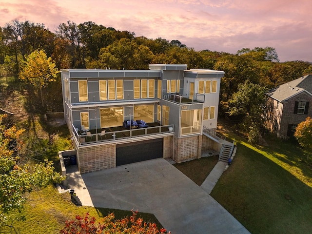 contemporary home with a garage, a balcony, and a lawn