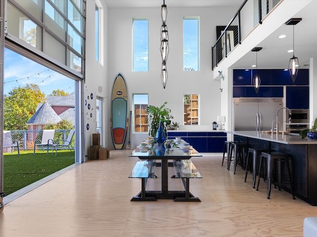 dining room with sink, a towering ceiling, a wealth of natural light, and light hardwood / wood-style flooring