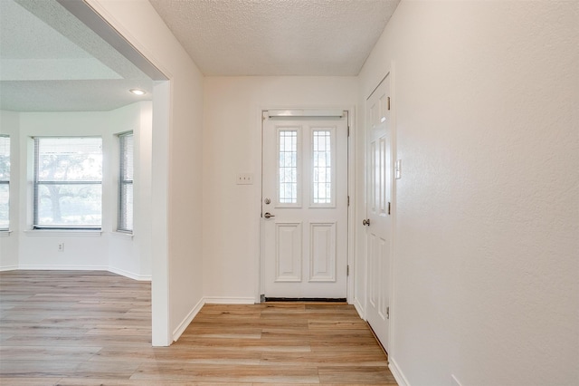 doorway featuring a textured ceiling and light hardwood / wood-style floors