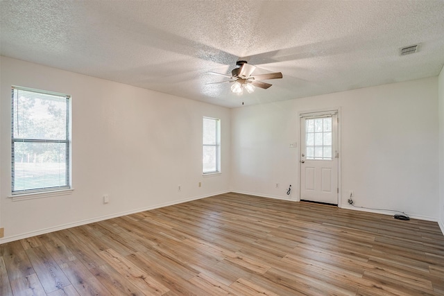 spare room featuring ceiling fan, plenty of natural light, a textured ceiling, and light wood-type flooring