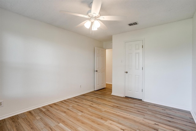 empty room featuring ceiling fan, light hardwood / wood-style floors, and a textured ceiling