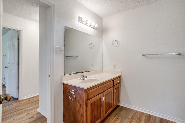 bathroom featuring vanity, wood-type flooring, and a textured ceiling