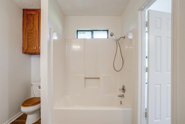 bathroom featuring hardwood / wood-style floors, toilet, a textured ceiling, and bathing tub / shower combination