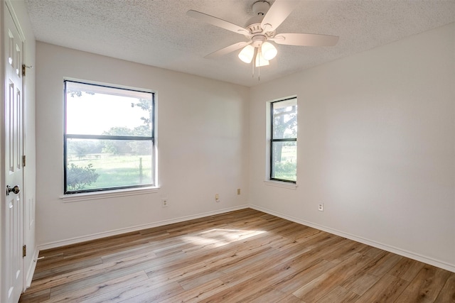 spare room with a textured ceiling, light wood-type flooring, and ceiling fan