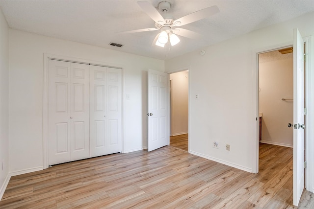 unfurnished bedroom featuring a textured ceiling, a closet, ceiling fan, and light hardwood / wood-style floors