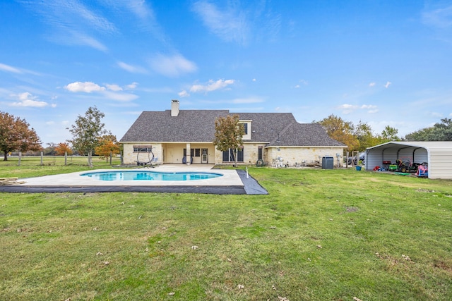 view of swimming pool featuring a lawn and a carport