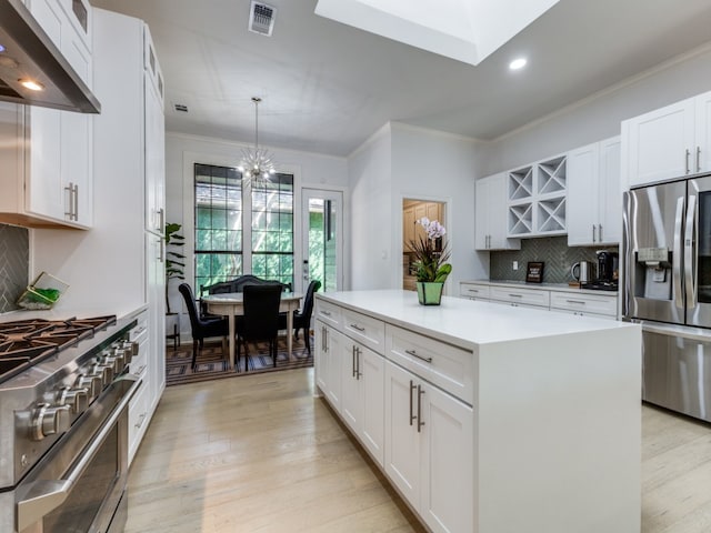 kitchen featuring white cabinetry, a center island, light hardwood / wood-style flooring, pendant lighting, and appliances with stainless steel finishes