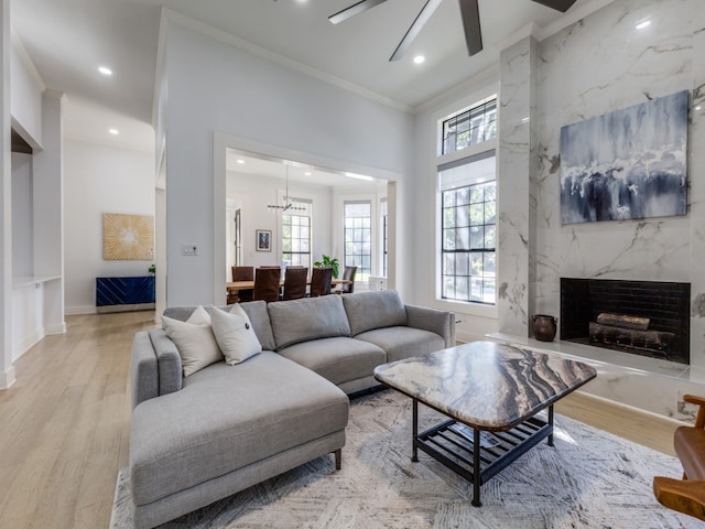 living room featuring a fireplace, light hardwood / wood-style flooring, ceiling fan, and crown molding