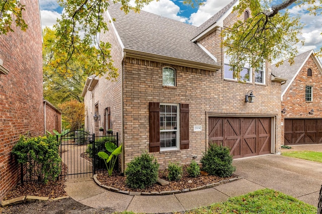 view of front facade featuring brick siding, roof with shingles, concrete driveway, fence, and a garage