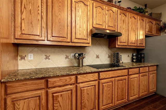 kitchen featuring dark hardwood / wood-style flooring, black electric stovetop, tasteful backsplash, and dark stone counters