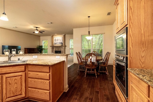 kitchen featuring hanging light fixtures, appliances with stainless steel finishes, a fireplace, and a sink