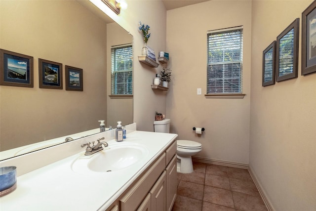 bathroom with baseboards, plenty of natural light, vanity, and toilet