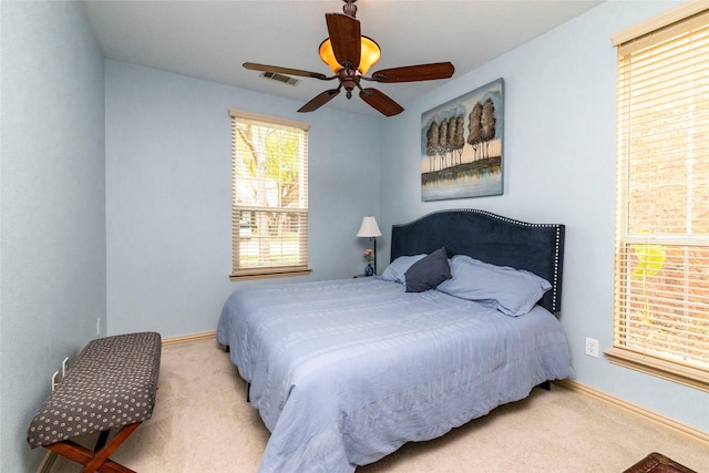 bedroom with light carpet, ceiling fan, visible vents, and baseboards