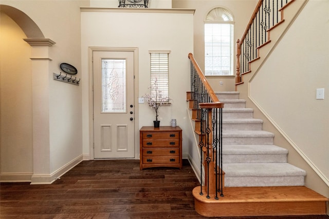 foyer entrance with decorative columns and dark hardwood / wood-style floors