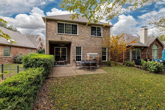 rear view of house featuring a patio area, fence, brick siding, and a lawn