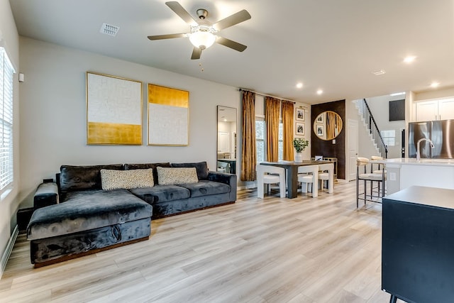 living room featuring ceiling fan and light hardwood / wood-style floors