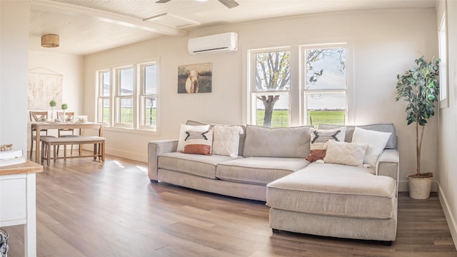 living room featuring attic access, an AC wall unit, baseboards, and wood finished floors