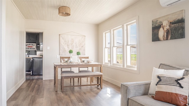 dining space featuring dark wood-style floors, a wall mounted air conditioner, and baseboards