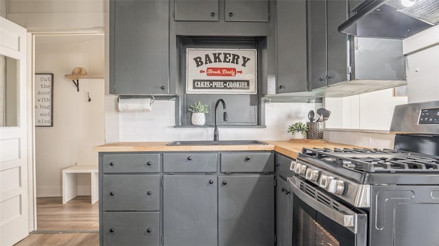 kitchen featuring stainless steel gas stove, gray cabinetry, a sink, and under cabinet range hood