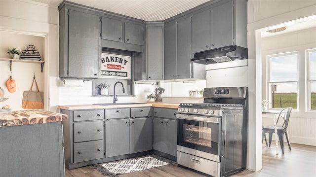 kitchen with gas range, wood finished floors, gray cabinetry, under cabinet range hood, and a sink