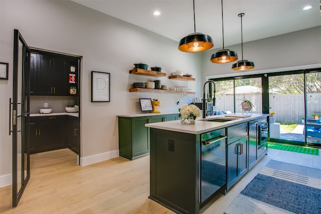 kitchen featuring pendant lighting, light hardwood / wood-style floors, sink, and a kitchen island with sink