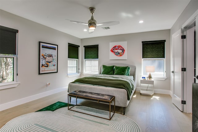 bedroom featuring multiple windows, light hardwood / wood-style floors, and ceiling fan