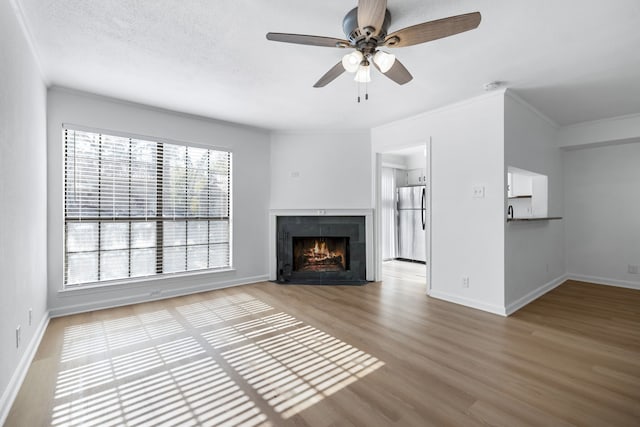 unfurnished living room with hardwood / wood-style floors, crown molding, ceiling fan, a fireplace, and a textured ceiling