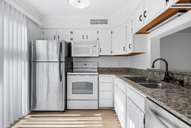 kitchen with stainless steel appliances, sink, dark stone countertops, and white cabinets