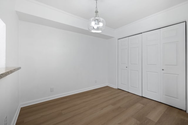 unfurnished bedroom with crown molding, hardwood / wood-style floors, a notable chandelier, and a closet