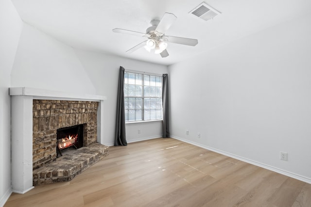 unfurnished living room featuring ceiling fan, a fireplace, and light wood-type flooring