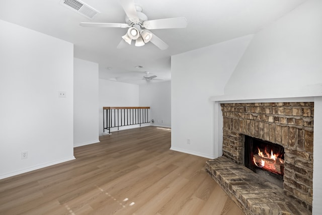 unfurnished living room with hardwood / wood-style floors, a brick fireplace, and ceiling fan