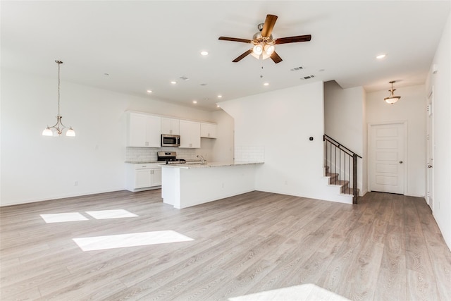 kitchen with hanging light fixtures, appliances with stainless steel finishes, white cabinets, and light stone counters