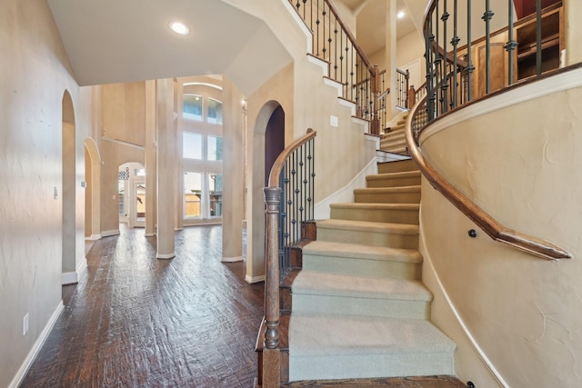 entryway with hardwood / wood-style floors and a towering ceiling