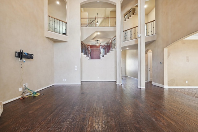 interior space with ceiling fan, a towering ceiling, and dark hardwood / wood-style floors