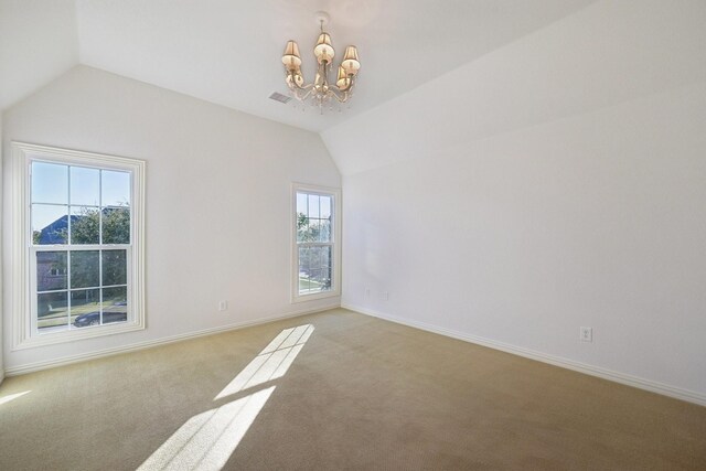 carpeted spare room with a chandelier, a wealth of natural light, and vaulted ceiling