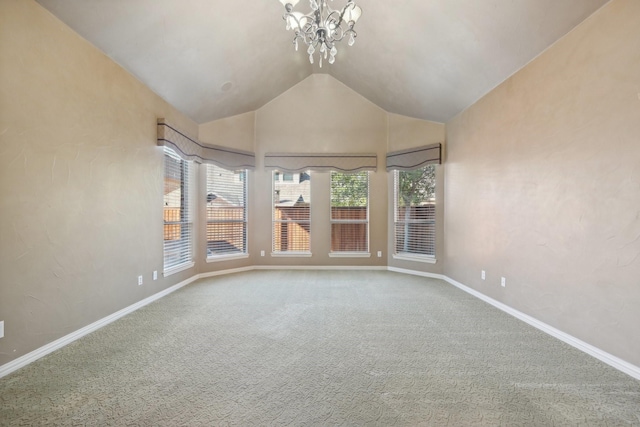 empty room with a chandelier, carpet floors, a wealth of natural light, and vaulted ceiling