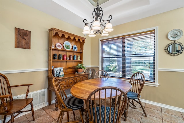 dining space with a notable chandelier, a tray ceiling, and light tile patterned floors