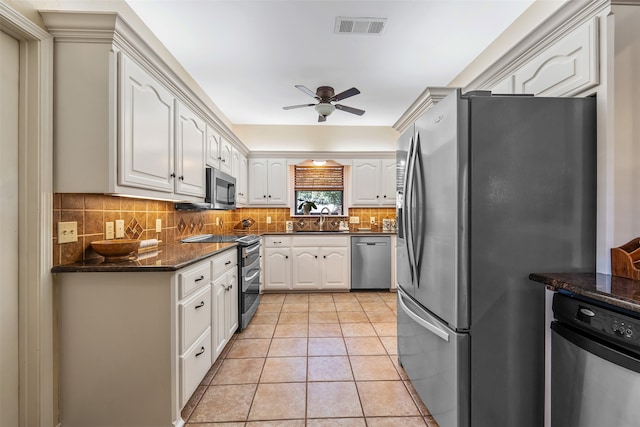 kitchen with appliances with stainless steel finishes, white cabinetry, dark stone countertops, backsplash, and ceiling fan