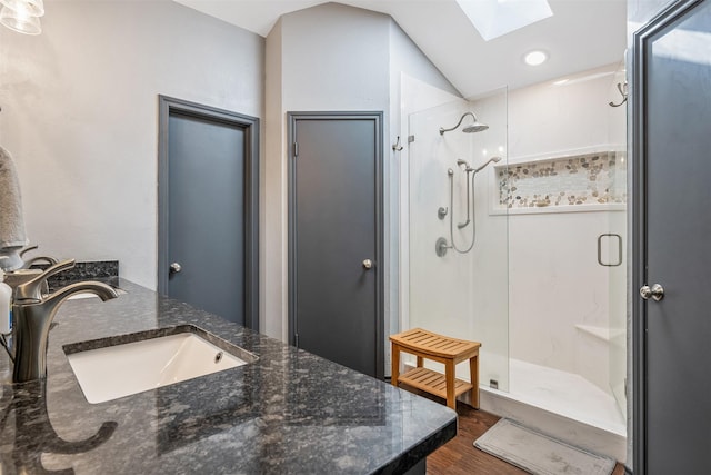 bathroom featuring vanity, lofted ceiling with skylight, hardwood / wood-style floors, and walk in shower