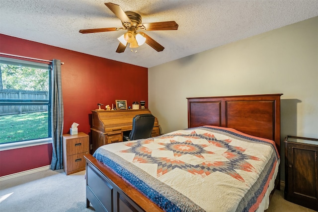 bedroom with ceiling fan, light colored carpet, and a textured ceiling