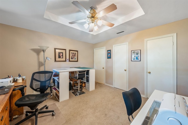 carpeted office featuring ceiling fan and a tray ceiling