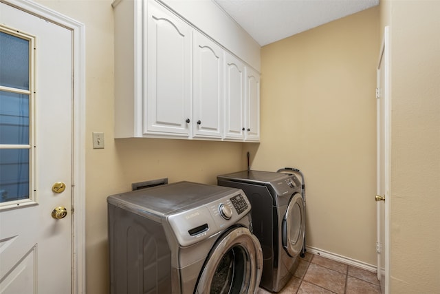 laundry area with cabinets, separate washer and dryer, and light tile patterned floors