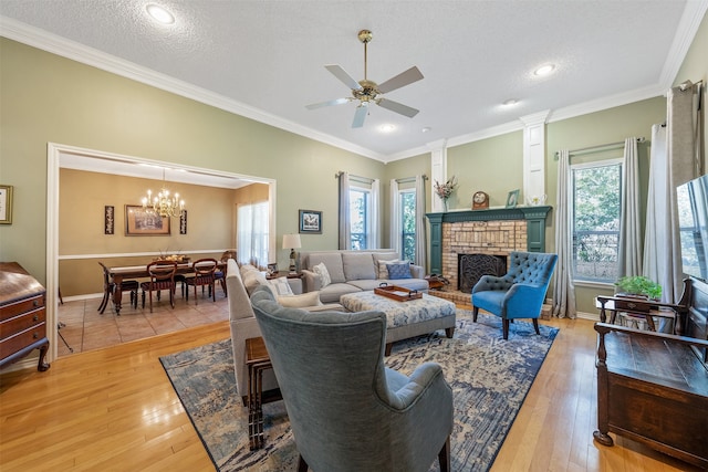 living room with ornamental molding, a healthy amount of sunlight, a brick fireplace, and light wood-type flooring