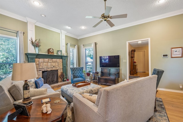 living room featuring wood-type flooring, ornamental molding, a textured ceiling, and a fireplace