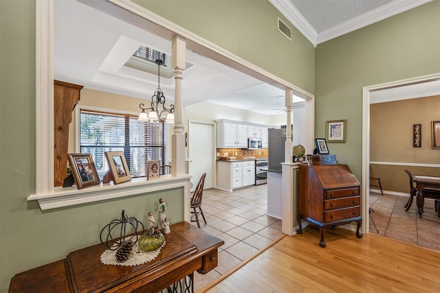 interior space with a notable chandelier, crown molding, light hardwood / wood-style floors, and a raised ceiling