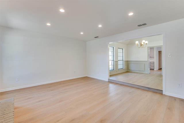 spare room with light hardwood / wood-style flooring and a chandelier