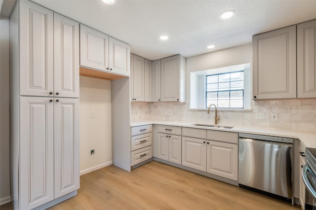 kitchen featuring tasteful backsplash, dishwasher, light hardwood / wood-style floors, and sink